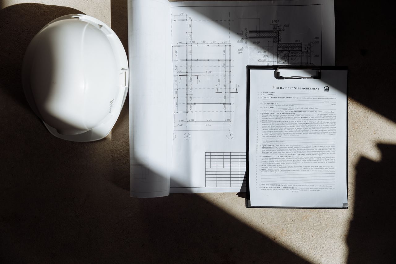 The Art of Drawing Readers In: Your attractive post title goes here Top view of construction documents and hard hat in sunlight, capturing planning essence.